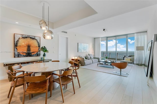 dining room featuring light wood-style floors, expansive windows, and visible vents