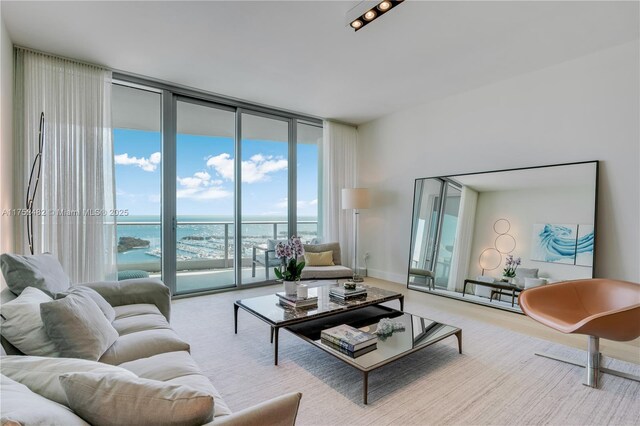 living area with expansive windows, a water view, and baseboards