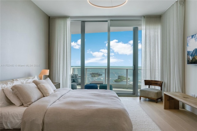 bedroom with access to outside, a wall of windows, and wood finished floors