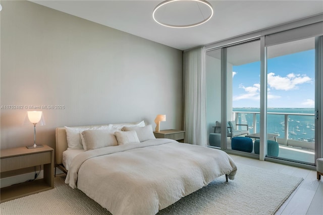 bedroom featuring access to outside, a wall of windows, and wood finished floors