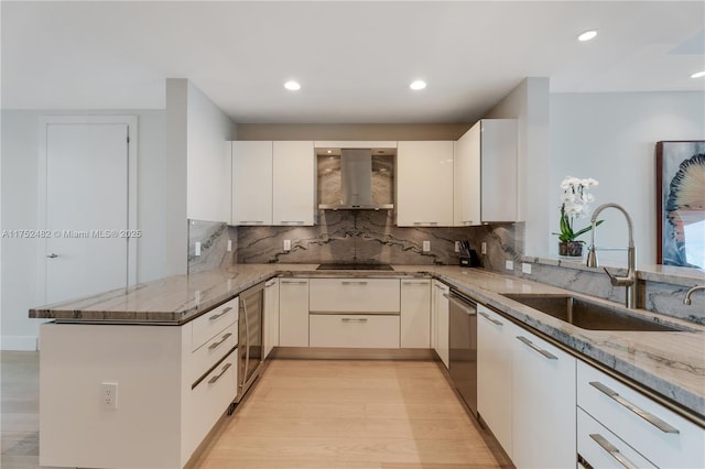 kitchen featuring a peninsula, light stone countertops, ventilation hood, and a sink