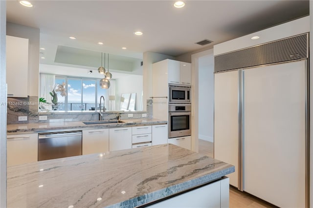 kitchen featuring visible vents, white cabinetry, a sink, modern cabinets, and built in appliances