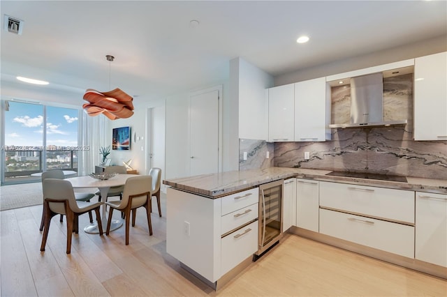 kitchen featuring black electric stovetop, wine cooler, a peninsula, visible vents, and wall chimney range hood