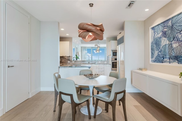 dining area with light wood finished floors, baseboards, visible vents, and recessed lighting