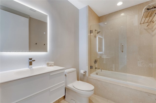 bathroom featuring toilet, tiled shower / bath, and vanity