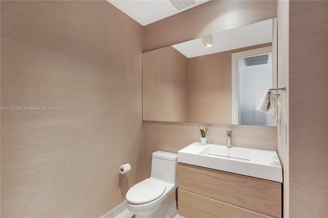 bathroom featuring toilet, vanity, and visible vents