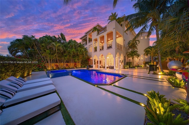 outdoor pool with a patio area, fence, and an in ground hot tub