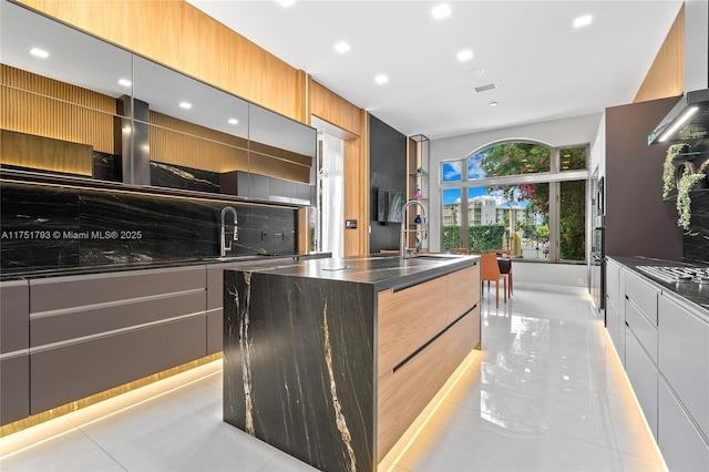 kitchen with modern cabinets, a sink, and a center island with sink