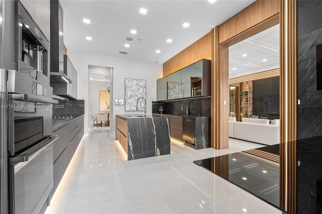 kitchen featuring a sink, visible vents, wall chimney exhaust hood, dark countertops, and modern cabinets