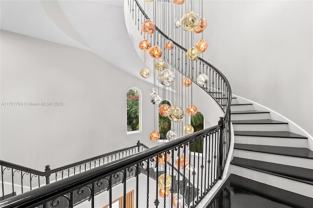 stairs with an inviting chandelier and a high ceiling