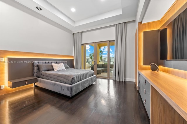 bedroom with access to outside, dark wood-type flooring, a tray ceiling, and visible vents