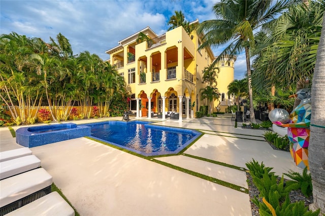 view of swimming pool featuring a pool with connected hot tub, fence, and a patio