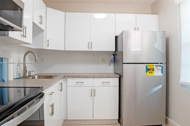 kitchen featuring stainless steel appliances, white cabinets, light countertops, and decorative backsplash