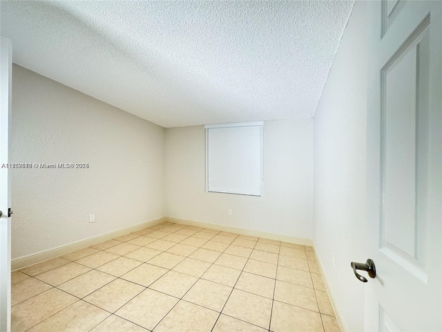 spare room with a textured ceiling and baseboards