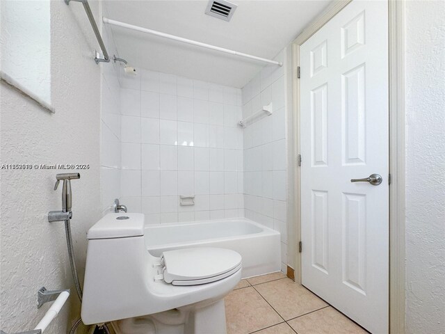 bathroom featuring visible vents, a textured wall, toilet, shower / tub combination, and tile patterned floors