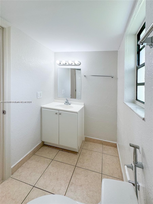 bathroom with tile patterned flooring, a textured wall, vanity, and baseboards