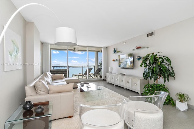 living area with floor to ceiling windows, a water view, and visible vents