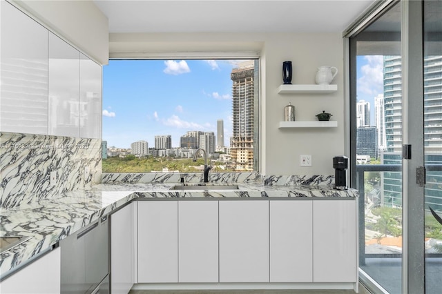 interior space with light stone counters, a view of city, and white cabinetry