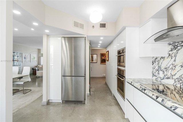 kitchen featuring visible vents, white cabinets, appliances with stainless steel finishes, wall chimney exhaust hood, and modern cabinets