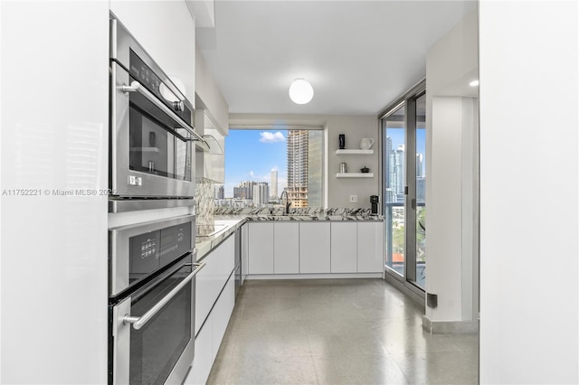 kitchen with a healthy amount of sunlight, white cabinets, a city view, and modern cabinets