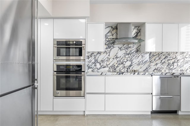 kitchen with decorative backsplash, appliances with stainless steel finishes, white cabinets, modern cabinets, and wall chimney exhaust hood