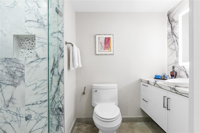 bathroom featuring toilet, a marble finish shower, baseboards, and vanity