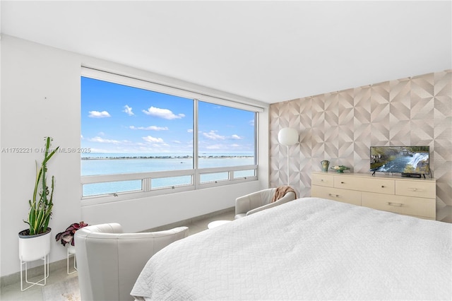 bedroom with an accent wall, a water view, baseboards, and multiple windows