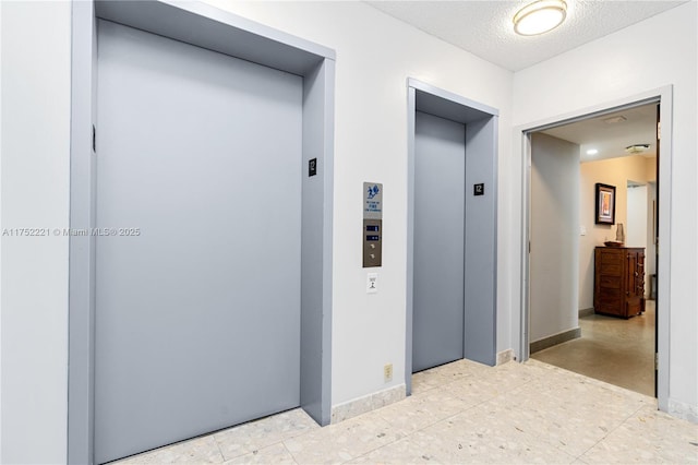 hallway featuring elevator, a textured ceiling, and baseboards