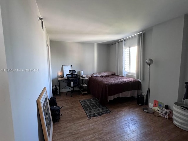 bedroom featuring heating unit and wood finished floors