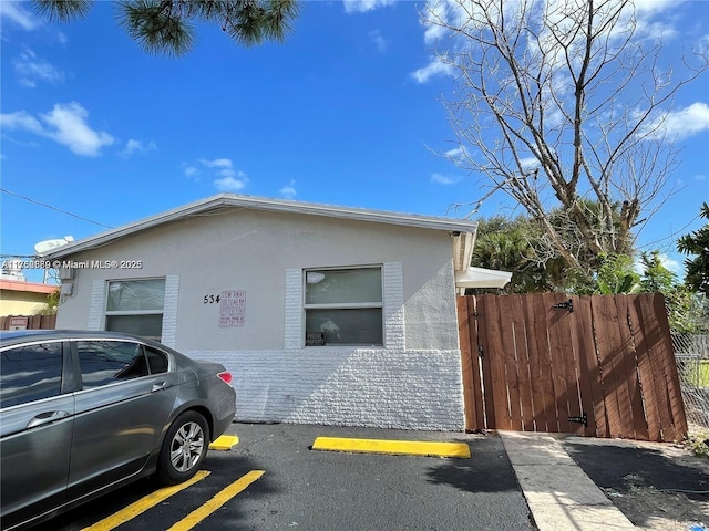 view of side of home featuring uncovered parking, fence, and stucco siding