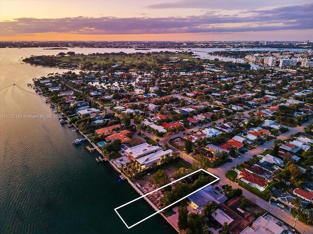 aerial view at dusk featuring a water view