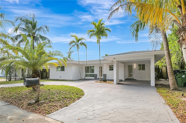 single story home with stucco siding, curved driveway, and a carport