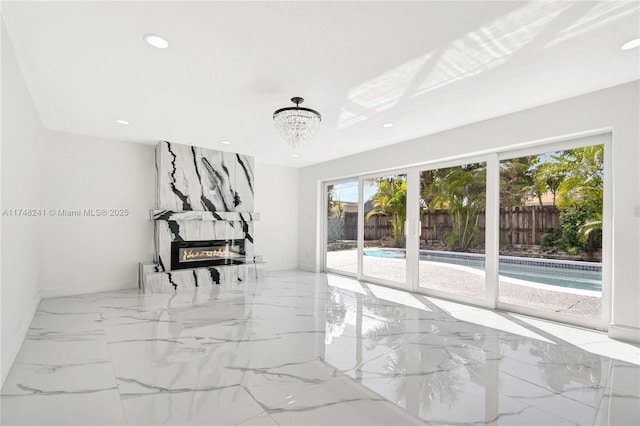 spare room featuring recessed lighting, french doors, a large fireplace, marble finish floor, and a chandelier