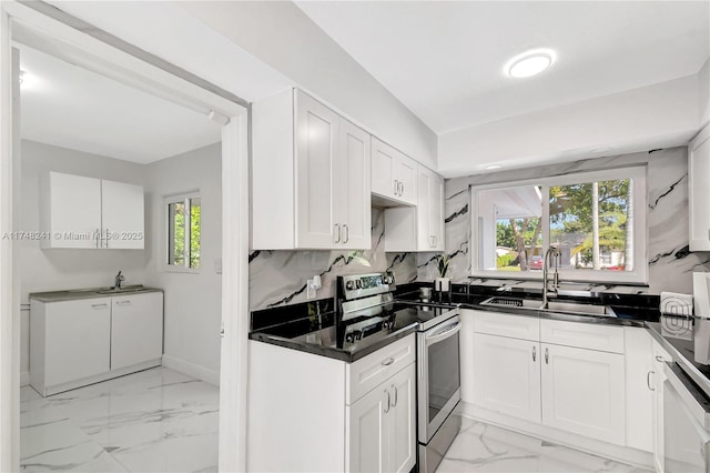 kitchen featuring marble finish floor, stainless steel range with electric cooktop, a healthy amount of sunlight, and a sink