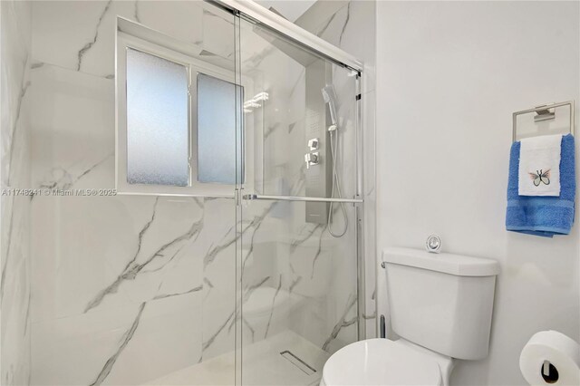 full bath featuring a marble finish shower and toilet