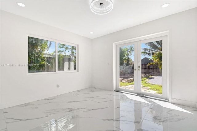 spare room featuring recessed lighting, plenty of natural light, french doors, and marble finish floor
