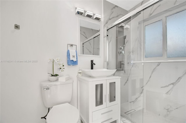 bathroom featuring a marble finish shower, toilet, marble finish floor, and vanity