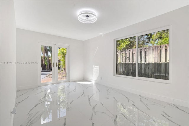 unfurnished room with marble finish floor, french doors, and baseboards