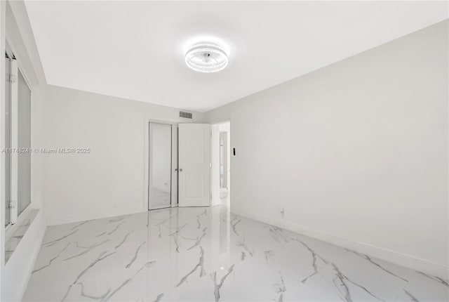 empty room with baseboards, visible vents, and marble finish floor
