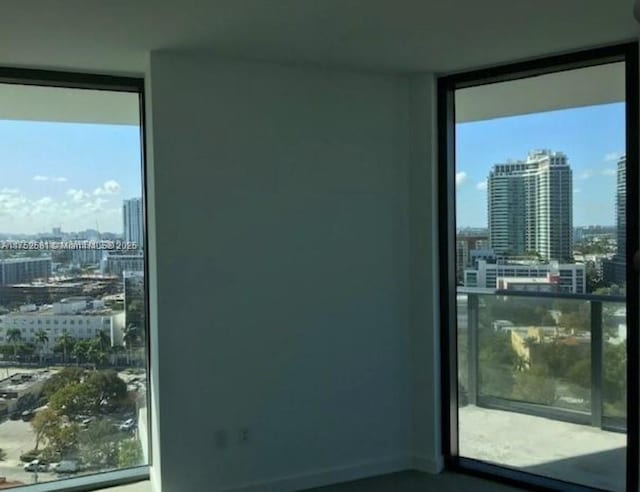 empty room with baseboards, a wall of windows, and a city view