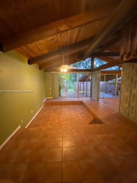 tiled empty room with wooden ceiling, lofted ceiling with beams, and baseboards