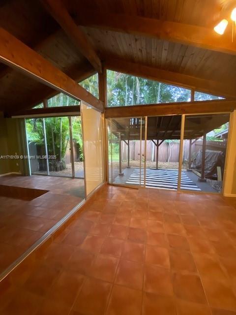 interior space featuring a healthy amount of sunlight, wooden ceiling, and vaulted ceiling with beams