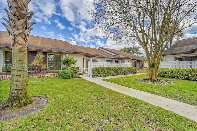 view of front of house with fence, a front lawn, and stucco siding