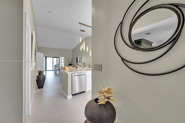 kitchen featuring marble finish floor, lofted ceiling, light countertops, stainless steel dishwasher, and white cabinetry