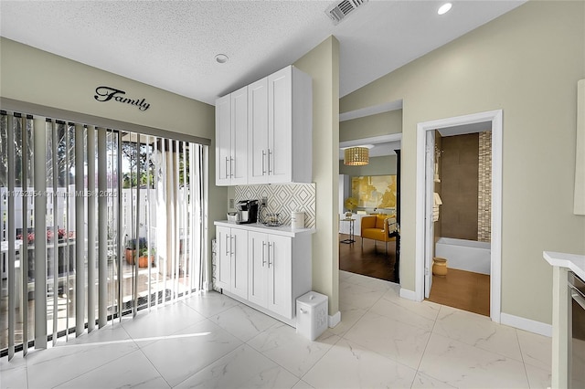 kitchen with marble finish floor, light countertops, visible vents, and white cabinetry