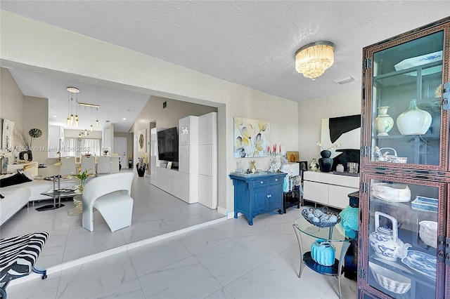 interior space featuring marble finish floor, a chandelier, and a textured ceiling