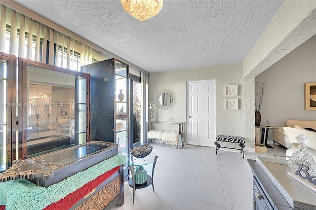 bedroom with marble finish floor, a textured wall, and a textured ceiling