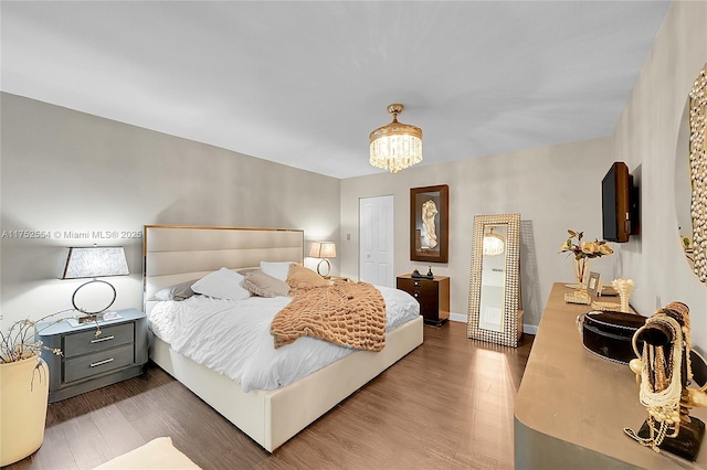 bedroom with baseboards, dark wood-style flooring, and an inviting chandelier