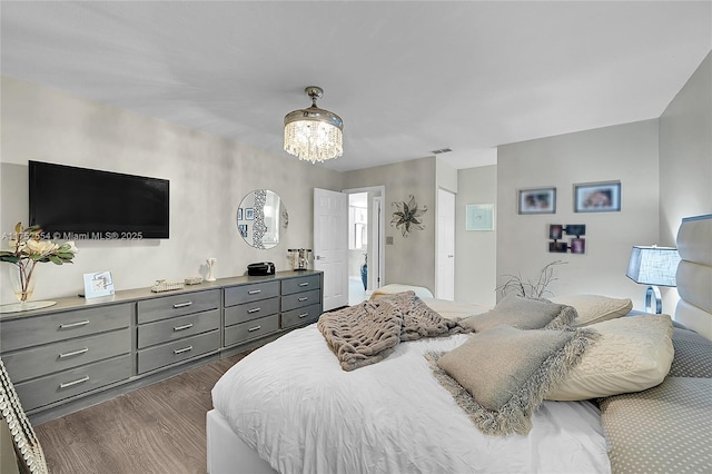 bedroom featuring dark wood finished floors, visible vents, and an inviting chandelier