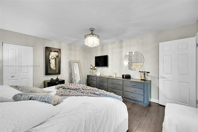 bedroom with a closet, dark wood-style flooring, a notable chandelier, and baseboards